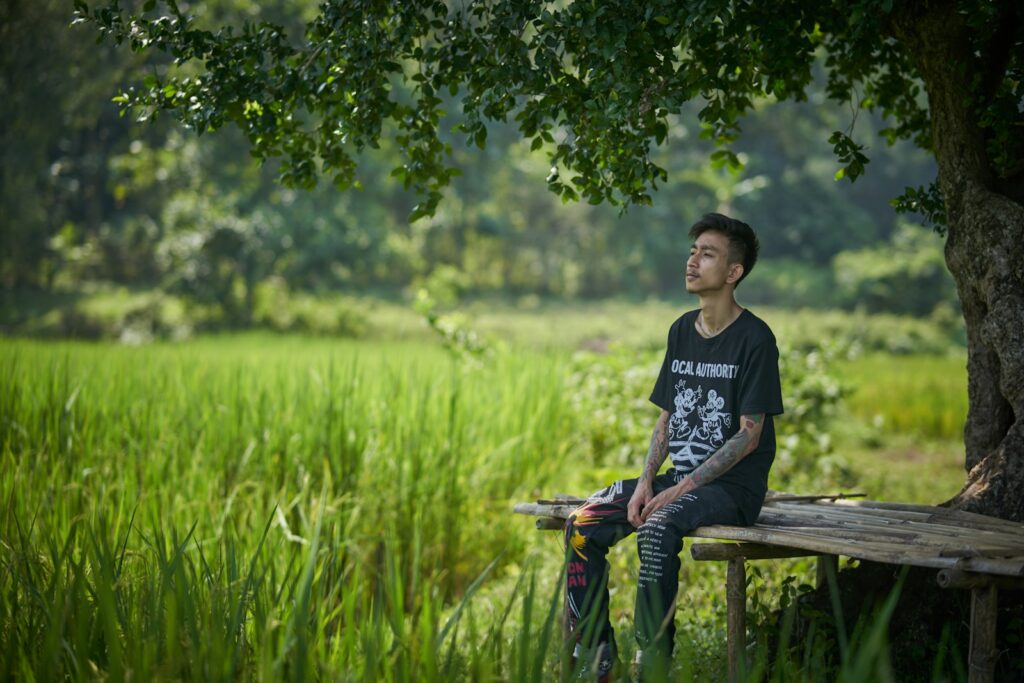 a man sitting on a wooden bench under a tree