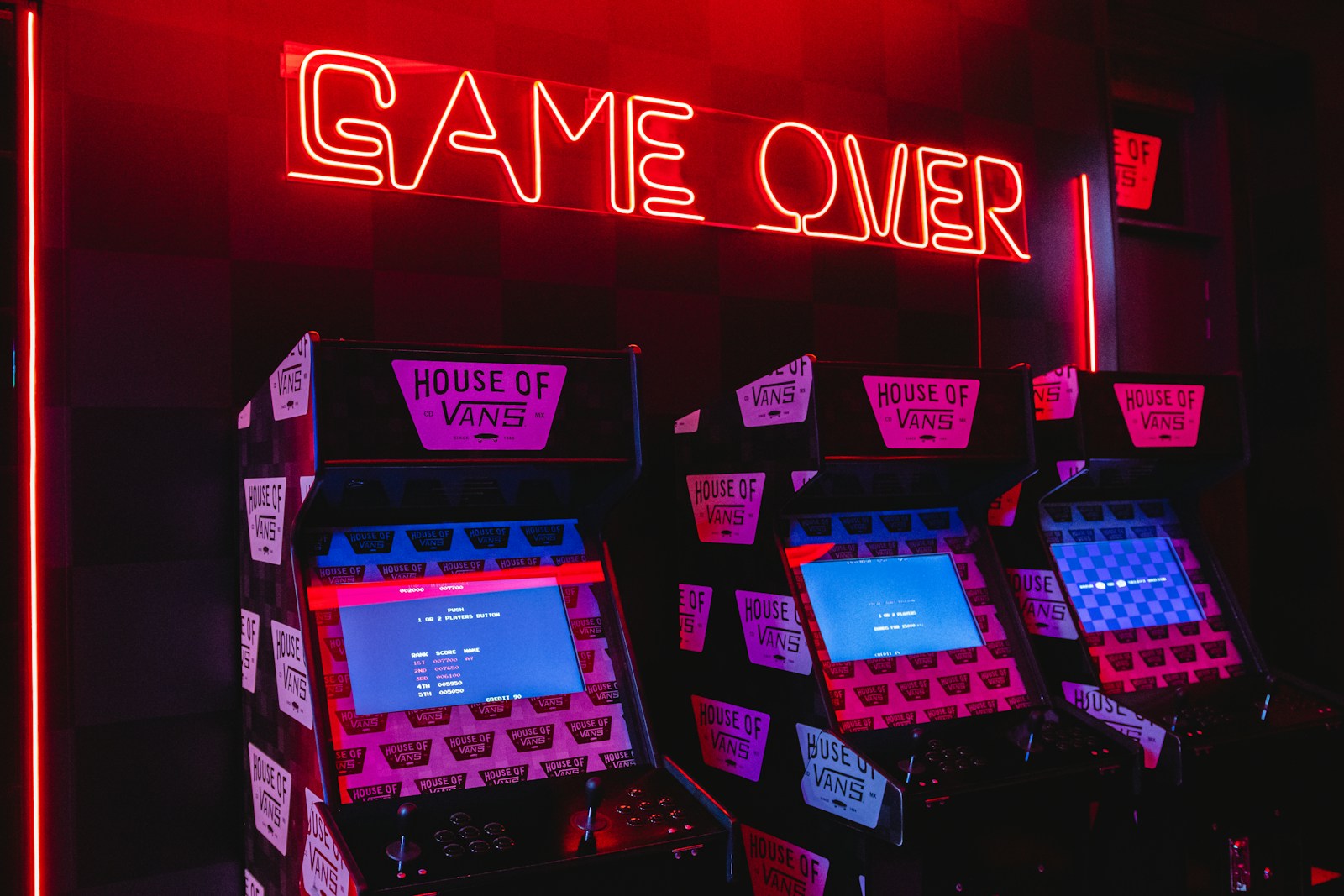 a neon sign that says game over in front of a row of arcade machines