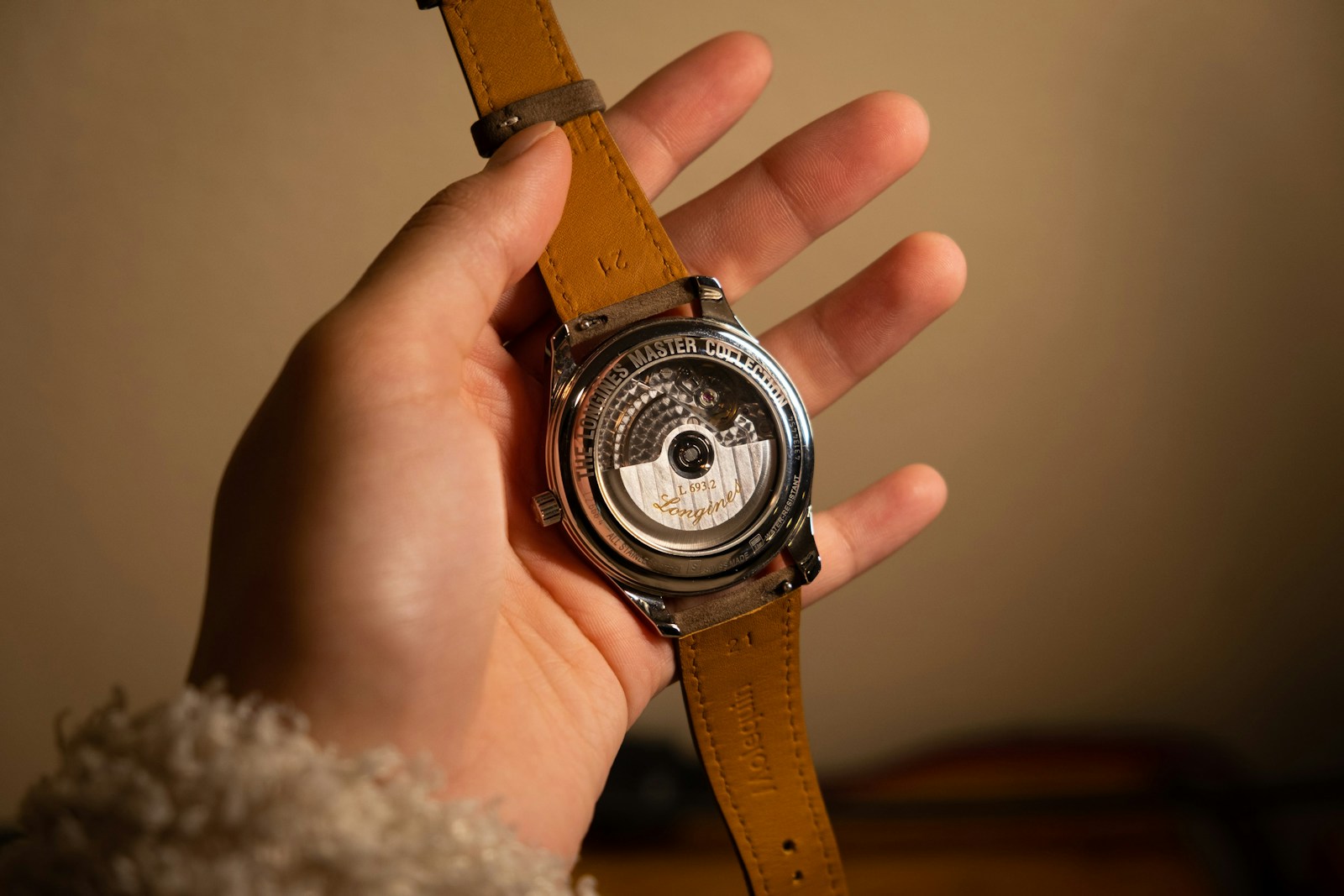 person holding brown leather strap silver round chronograph watch