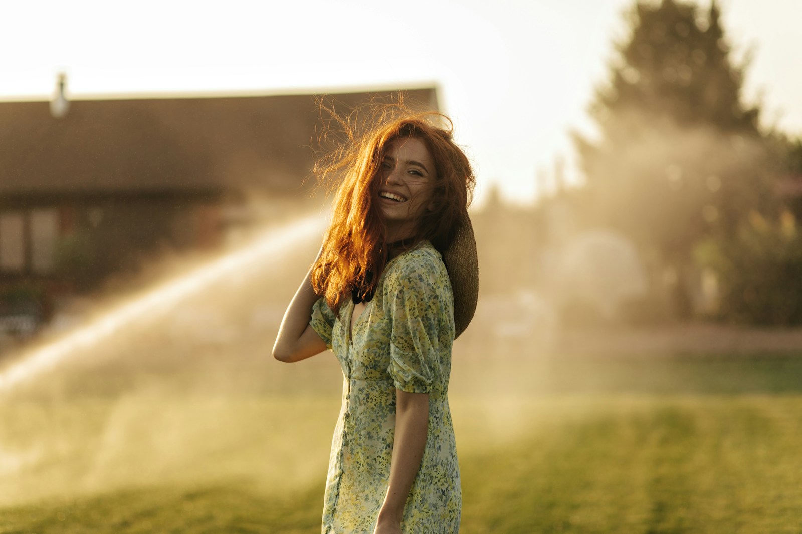 a woman standing in a field with a sprinkle of water behind her