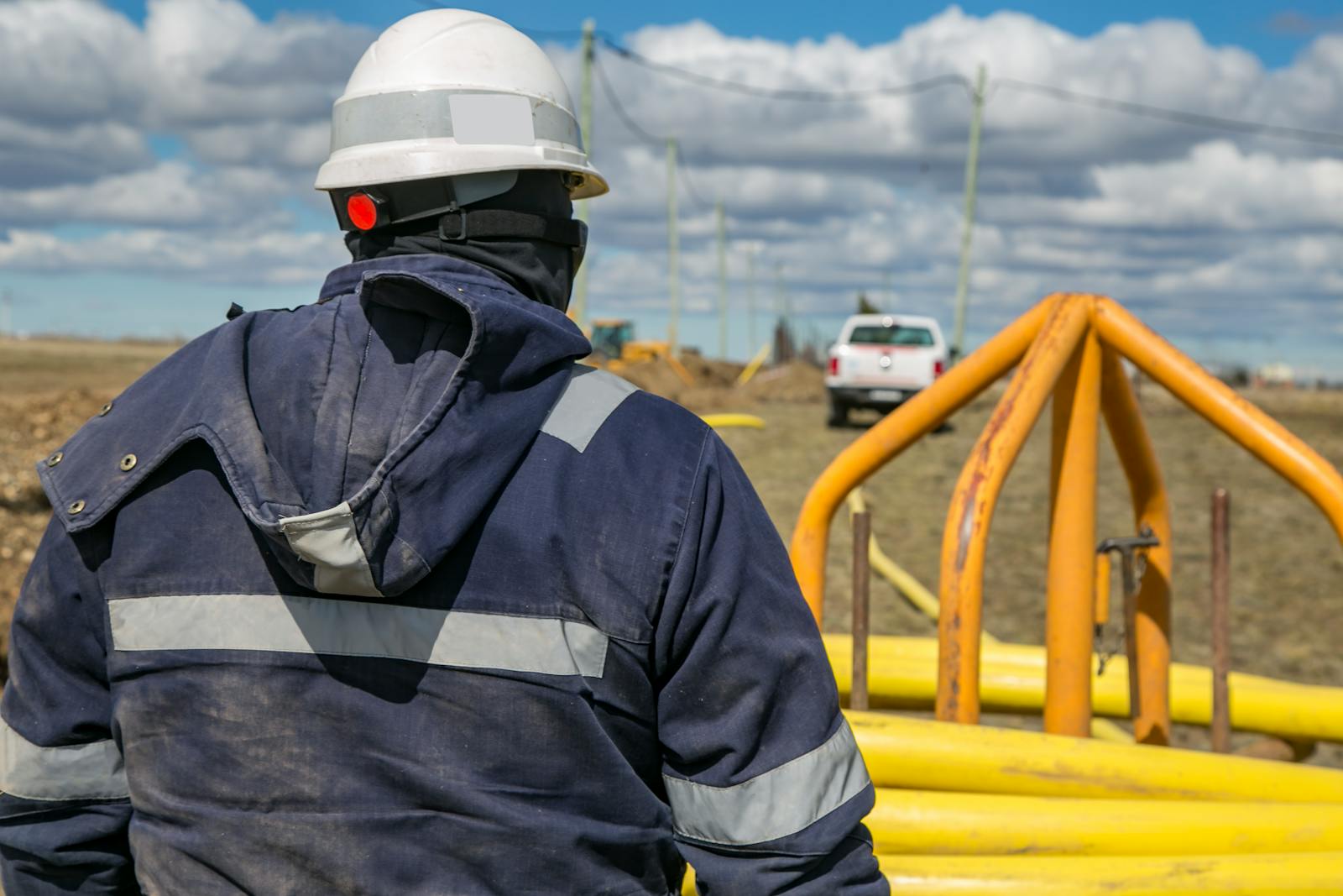 A construction worker in protective gear observing a site on a sunny day.