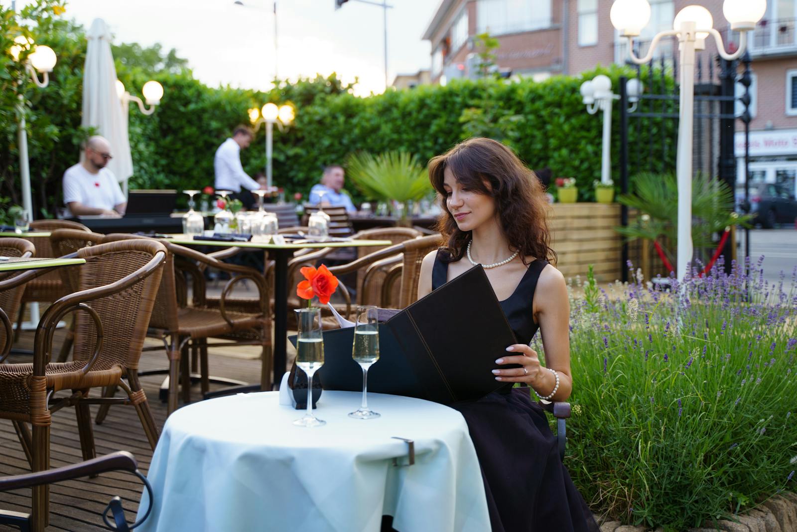A woman enjoys a romantic dinner outdoors with champagne, perfect for a date night.