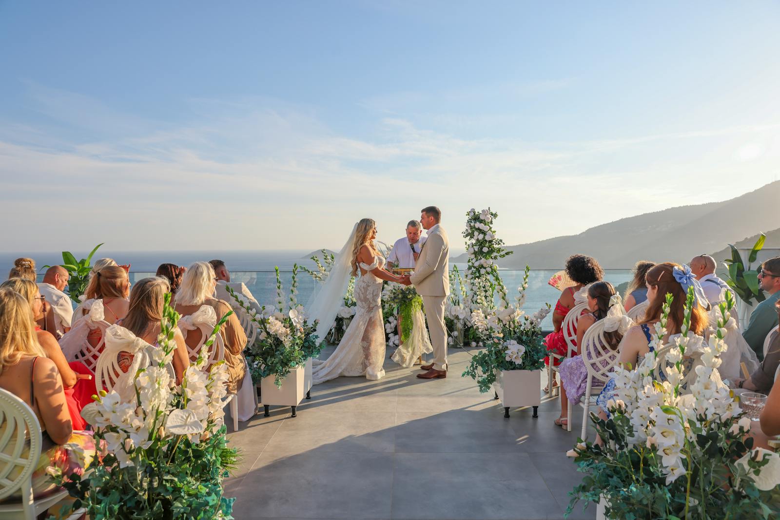Elegant outdoor wedding ceremony with ocean view and floral decor.