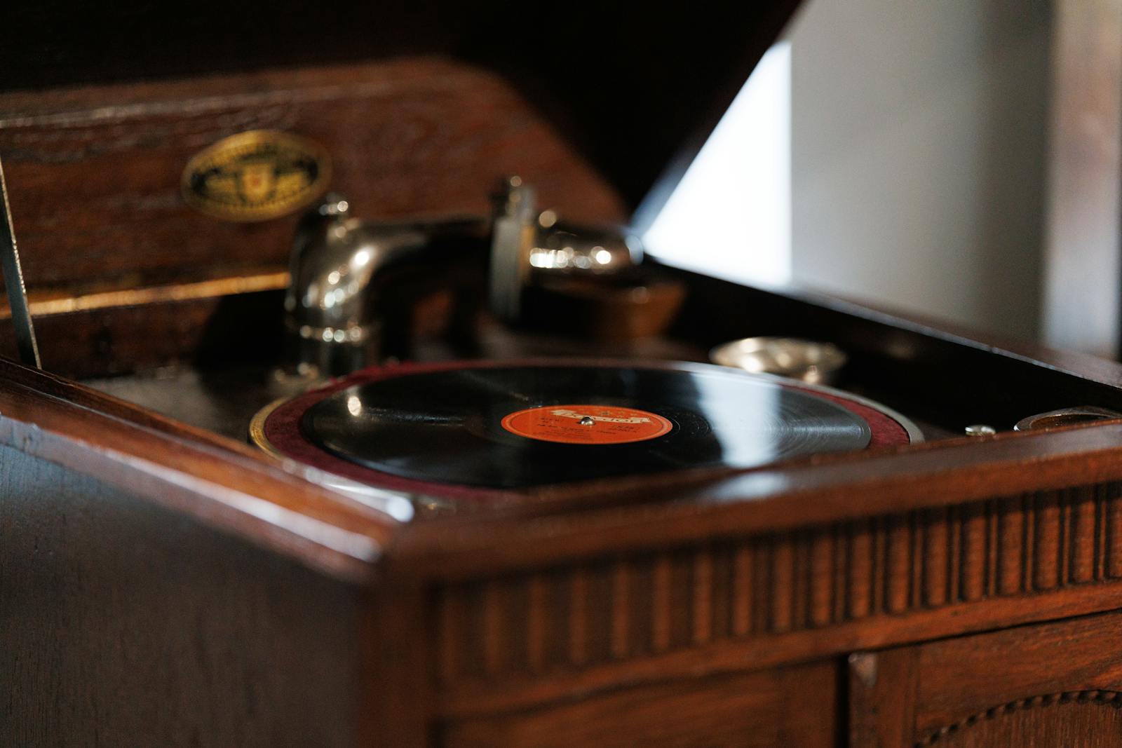 Close-up of a vintage wooden record player with a black vinyl record, evoking nostalgia.
