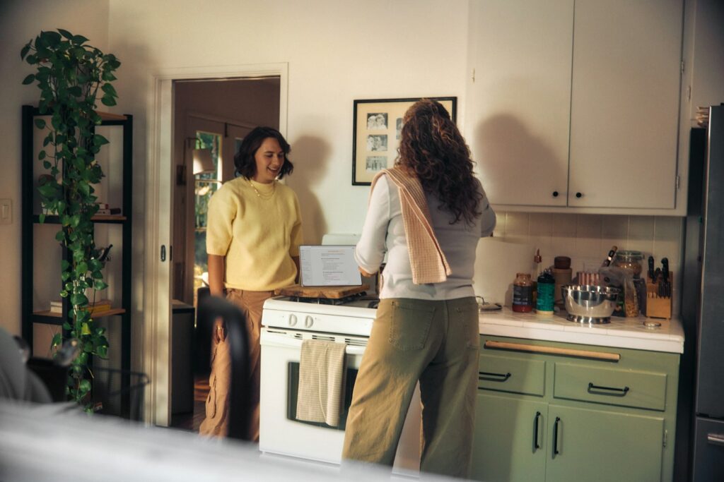 Two women talking in a kitchen while cooking