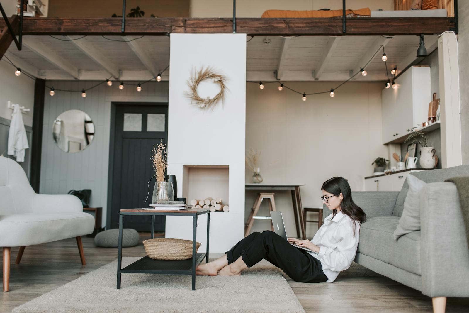 Cozy loft apartment with a woman working on a laptop, showcasing modern remote work lifestyle.