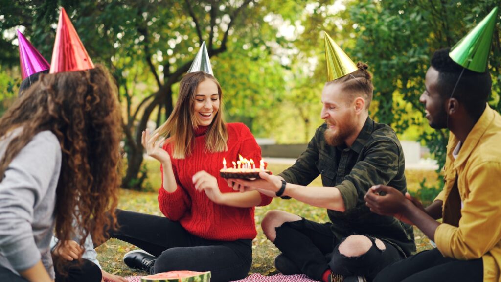 Friends celebrating birthday with cake in park