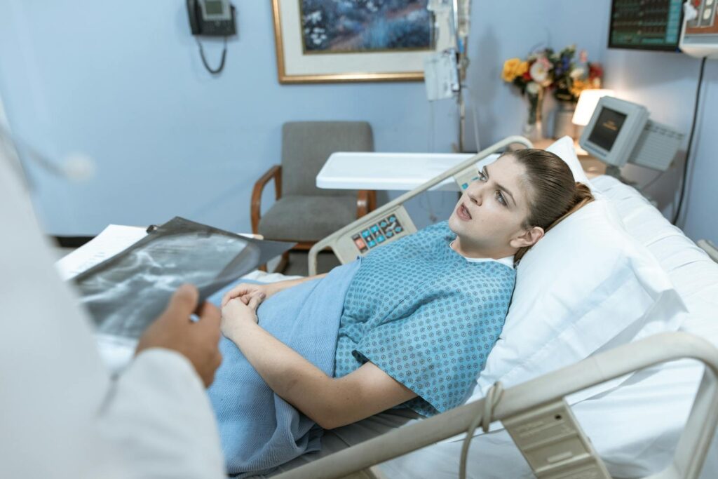 Caucasian woman in hospital bed receiving care from healthcare professional.