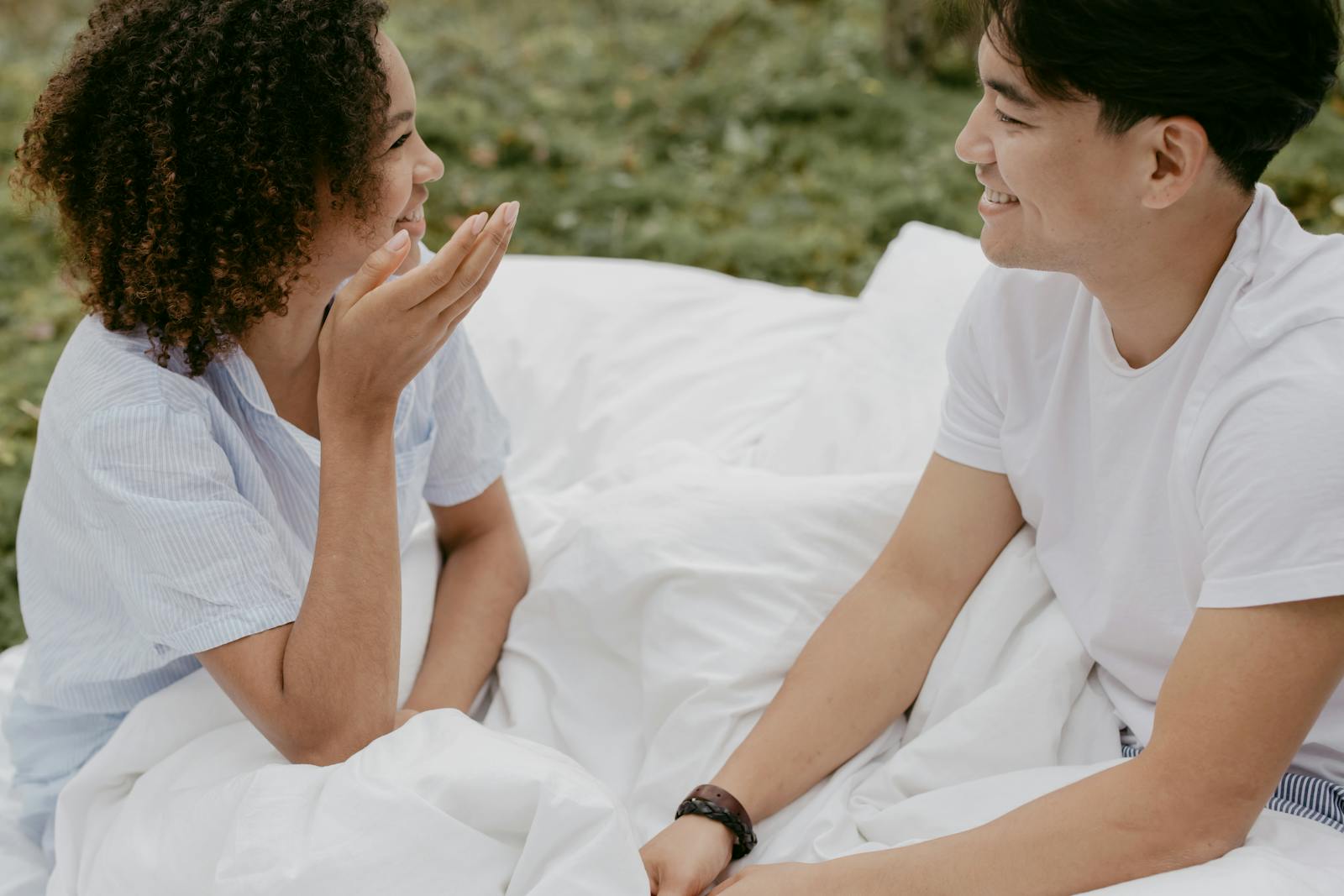A happy couple smiling and chatting outdoors in a relaxed, romantic setting.