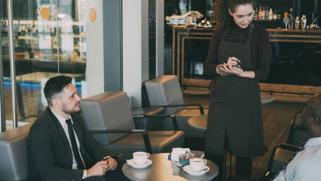 Waitress takes order from customers in cafe.