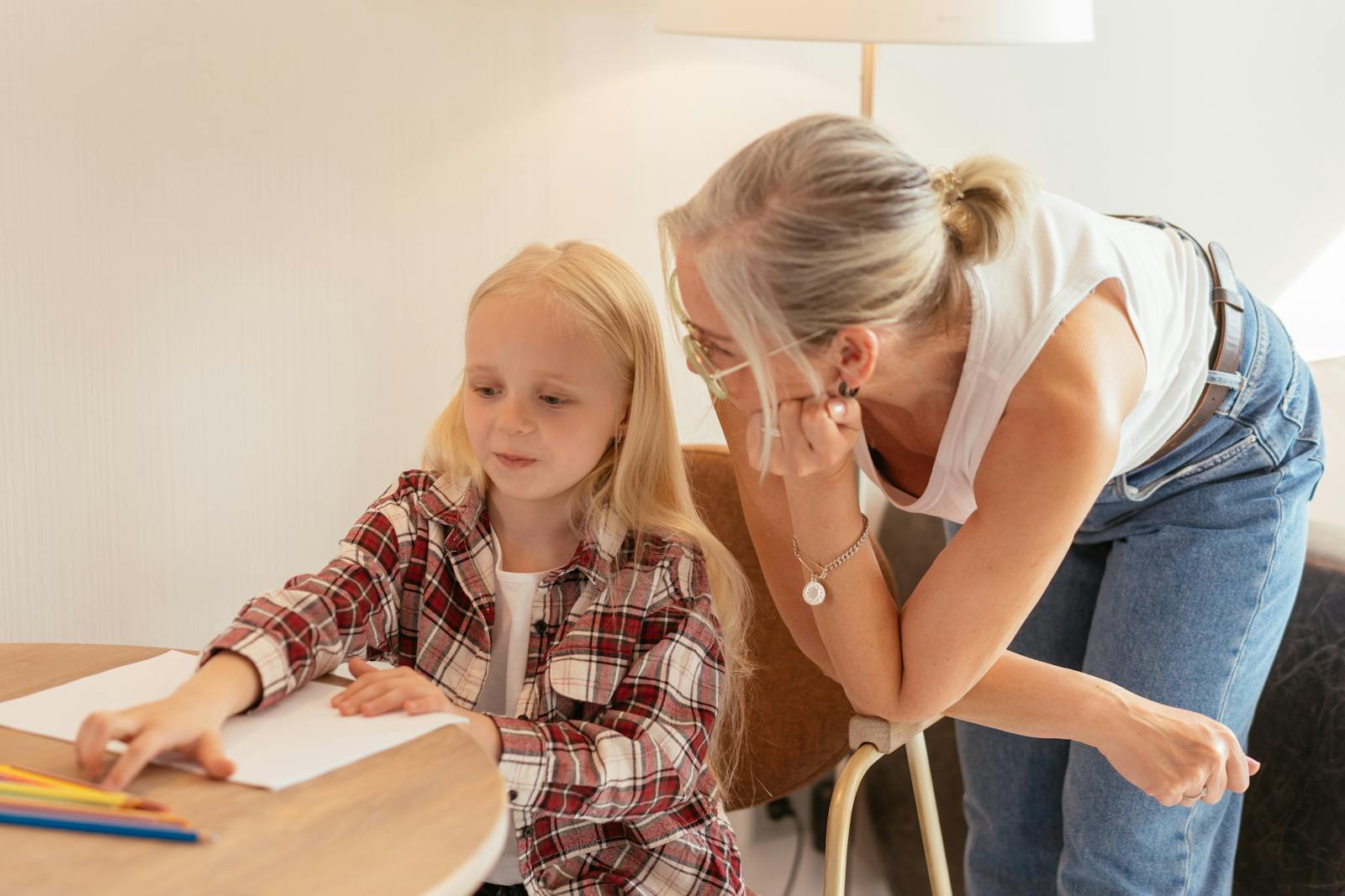 Elderly woman teaching young girl at home, fostering learning and connection.