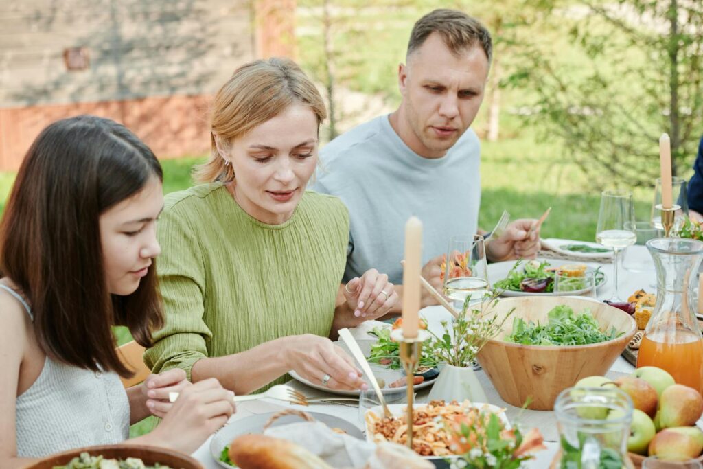 A family shares a meal outdoors, enjoying fresh and vibrant salads.