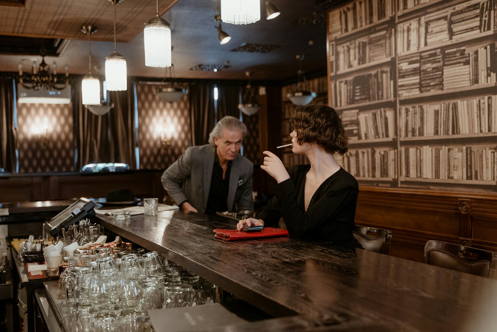 A stylish woman and a gentleman in a classic bar setting, exuding glamour and elegance.