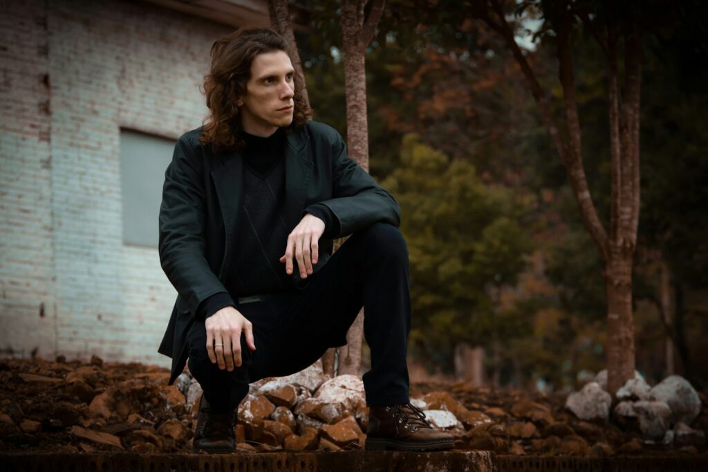 woman in black jacket and black pants sitting on brown rock