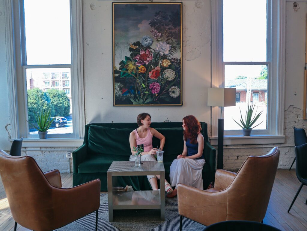 Two women are talking on a green couch.
