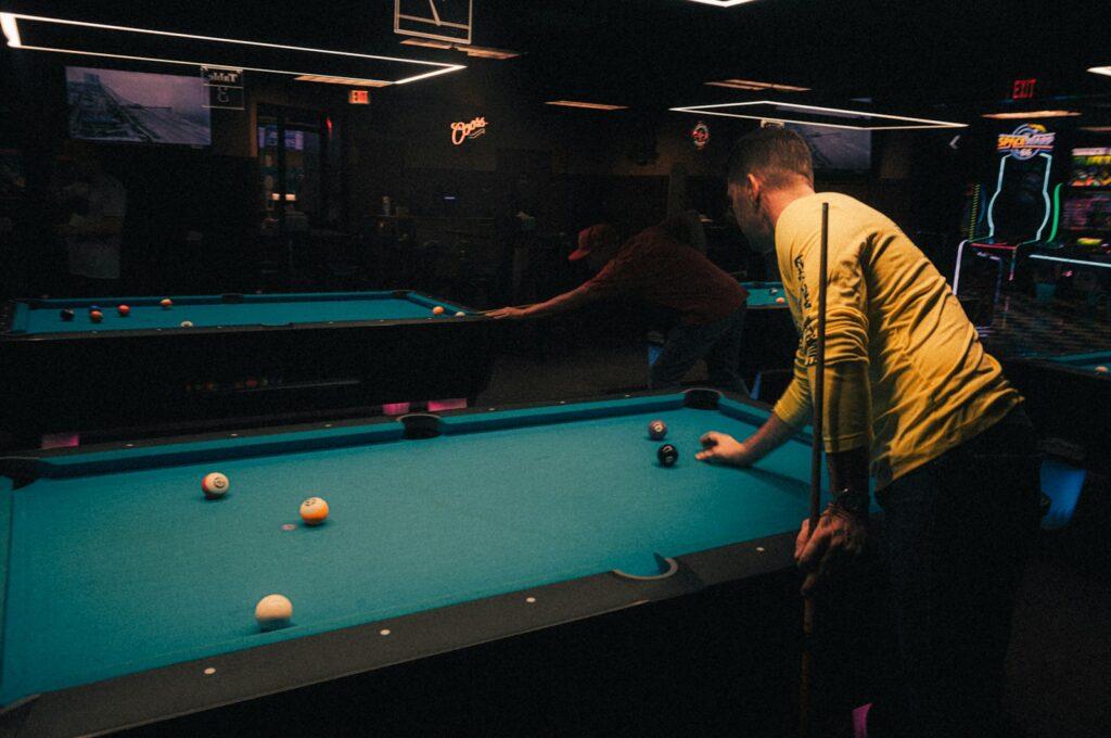 Two men playing pool in a dark room