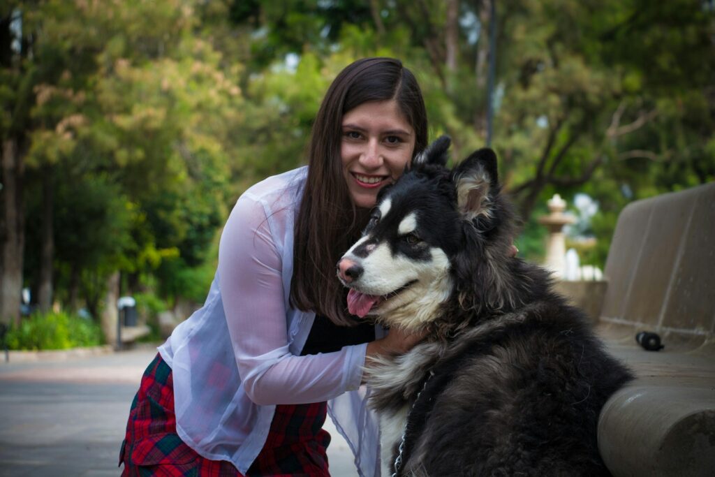 woman in black long sleeve shirt hugging black and white siberian husky