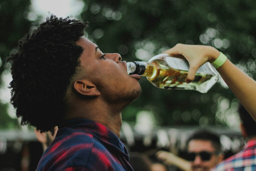 man drinking from clear glass bottle