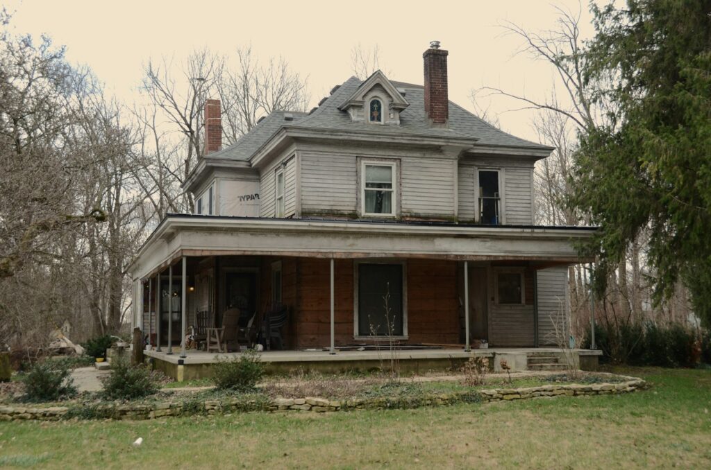 An old, weathered house with a large porch.
