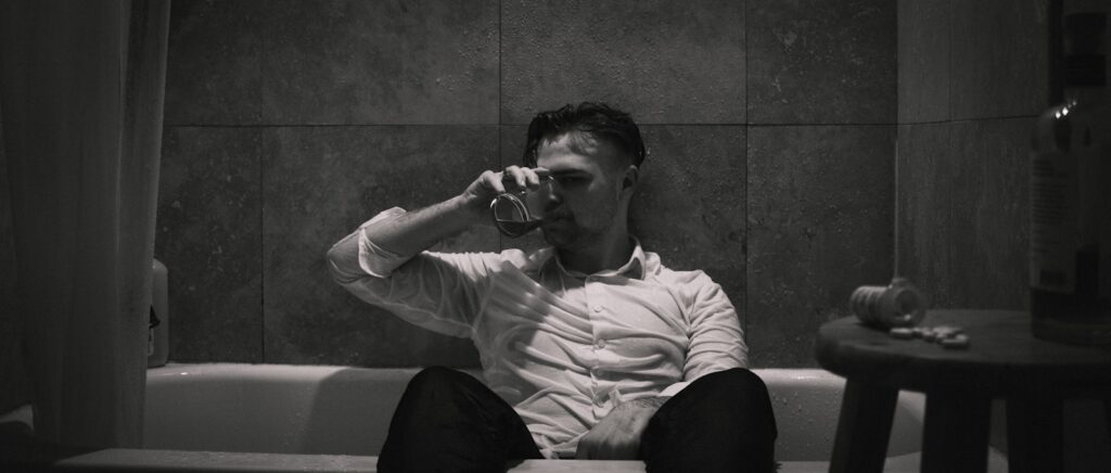 man in white and pink stripe dress shirt sitting on green floor tiles