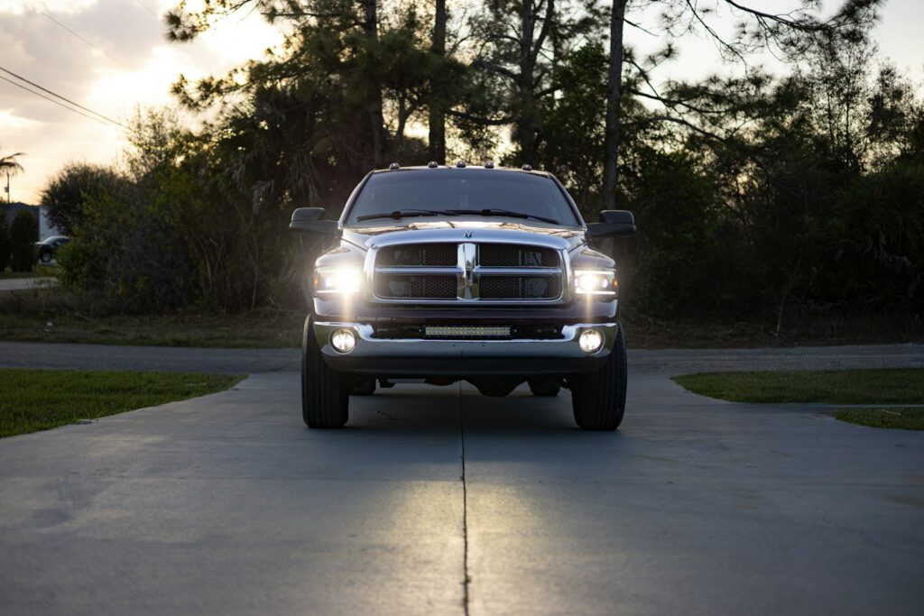 Silver pickup truck with headlights on driveway