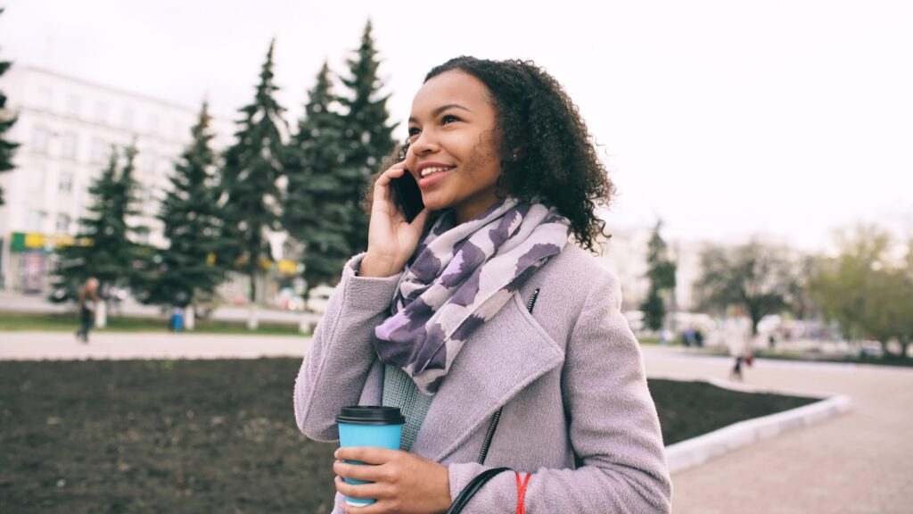 Young woman talking on phone holding coffee cup