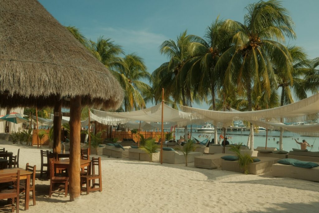 Beach resort with palm trees and lounge chairs.