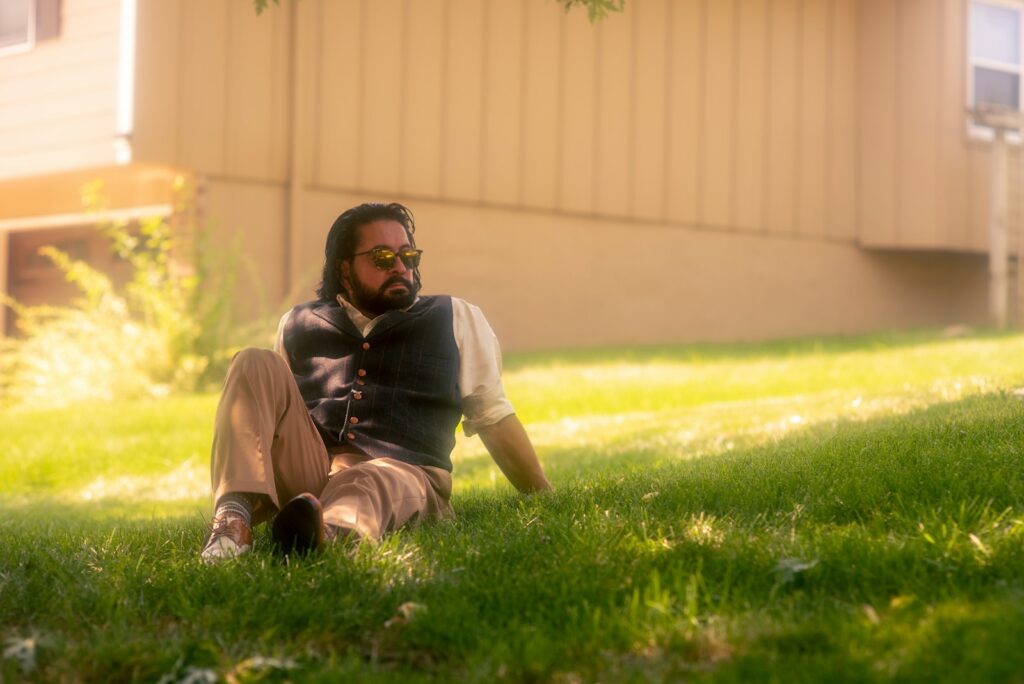 man in white shirt and brown pants sitting on green grass field