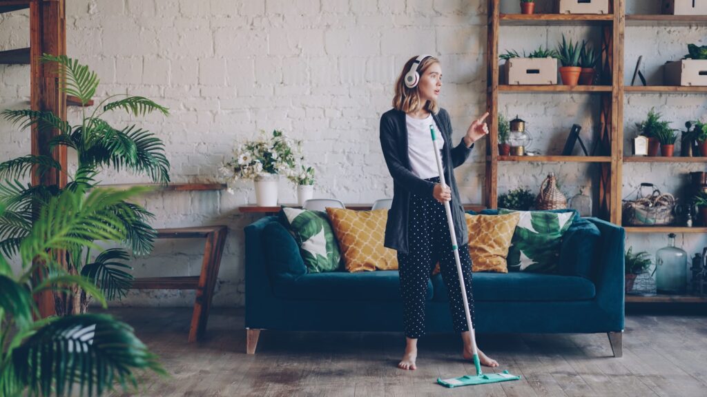 Woman with headphones mopping floor and dancing