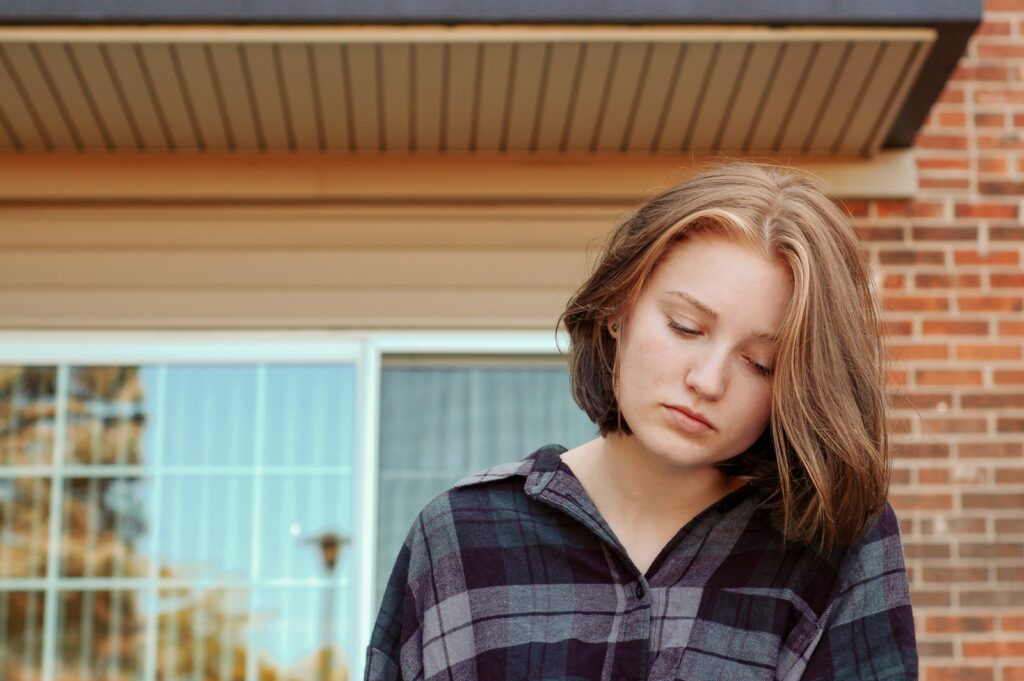 woman looks down outside red brick building