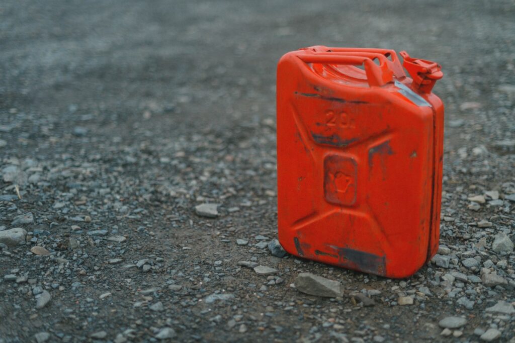 An orange gas can sitting on the ground