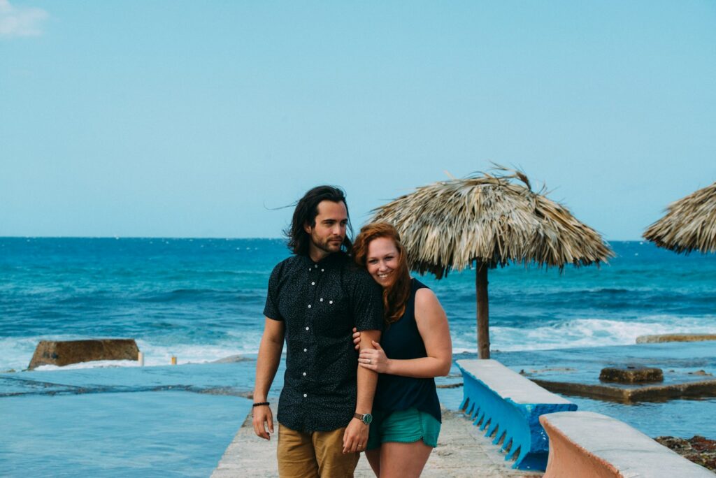 Couple walking on a pier by the ocean.