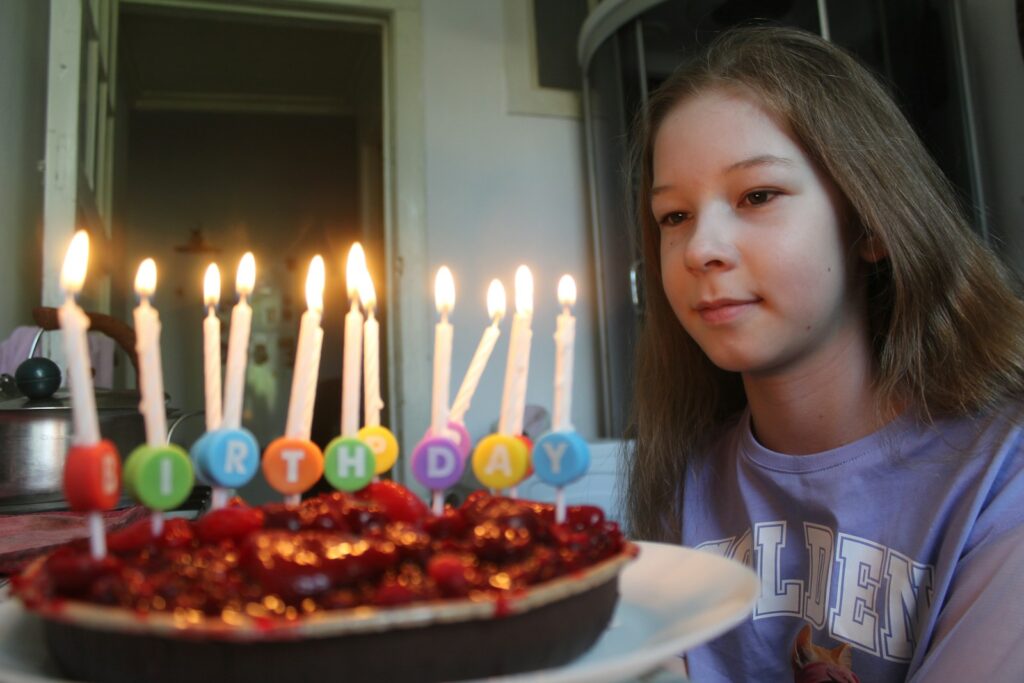 Girl looking at birthday cake with lit candles