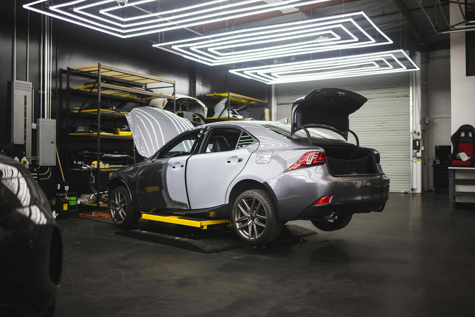Gray car undergoing repairs in a sleek, modern auto repair shop environment.