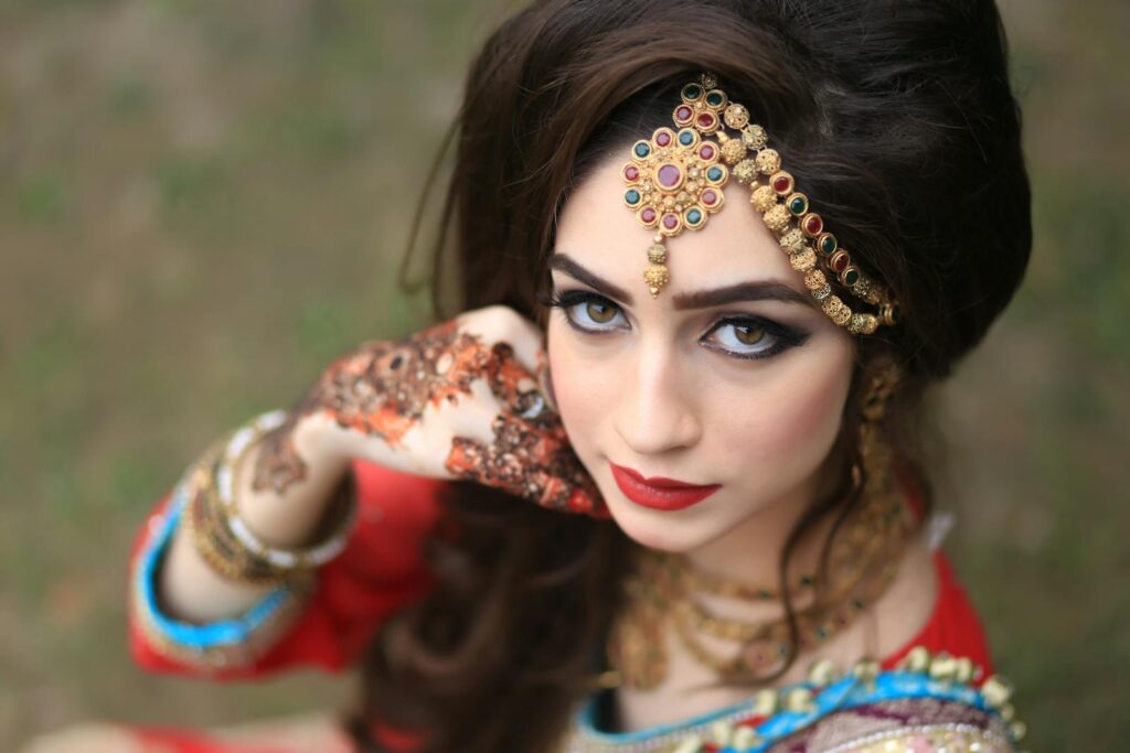Stunning portrait of a South Asian woman adorned in traditional jewelry and henna, showcasing beauty and elegance.