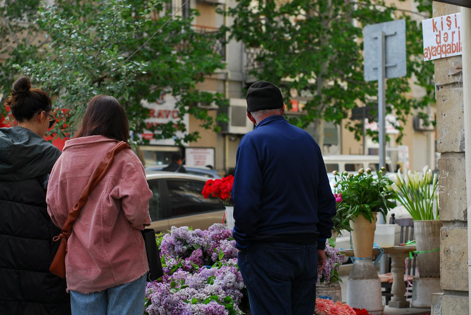 People shopping at a vibrant flower stand on a city sidewalk, showcasing urban life.