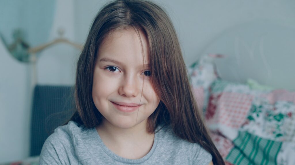 A young girl smiles directly at the camera.