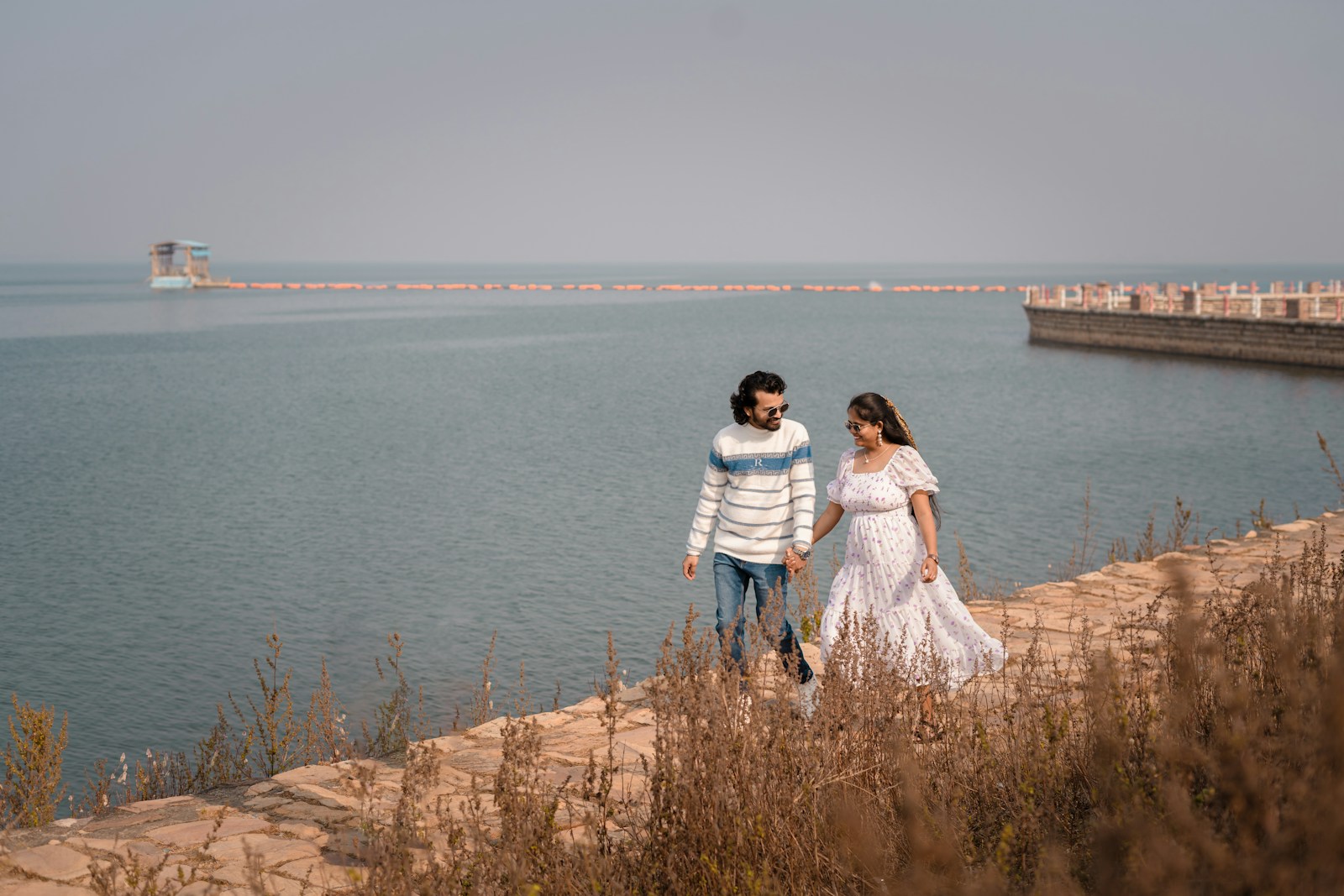 Couple walking by the water with a distant structure