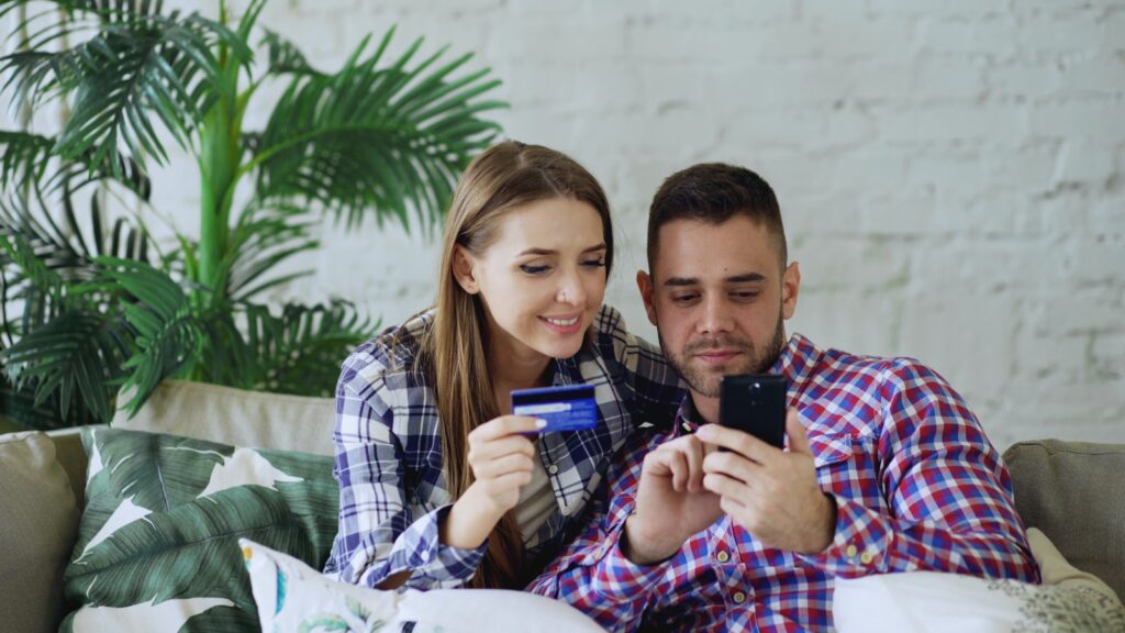 Couple happily shopping online with credit card and phone.