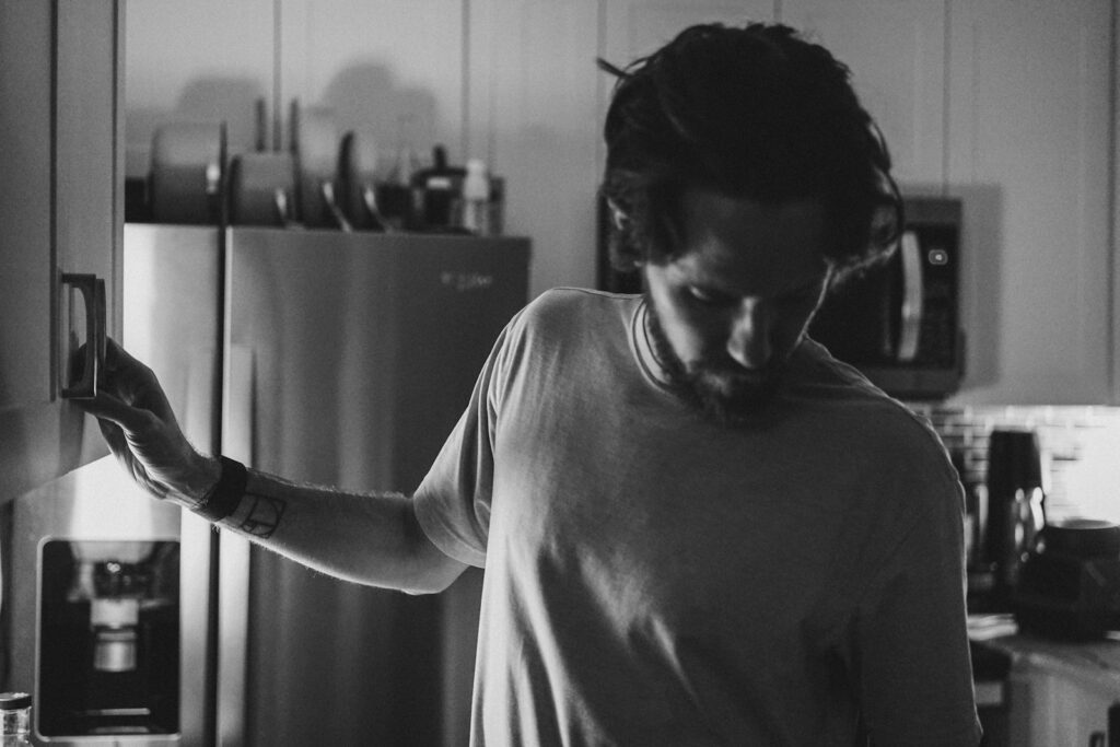 a man standing in a kitchen next to a refrigerator