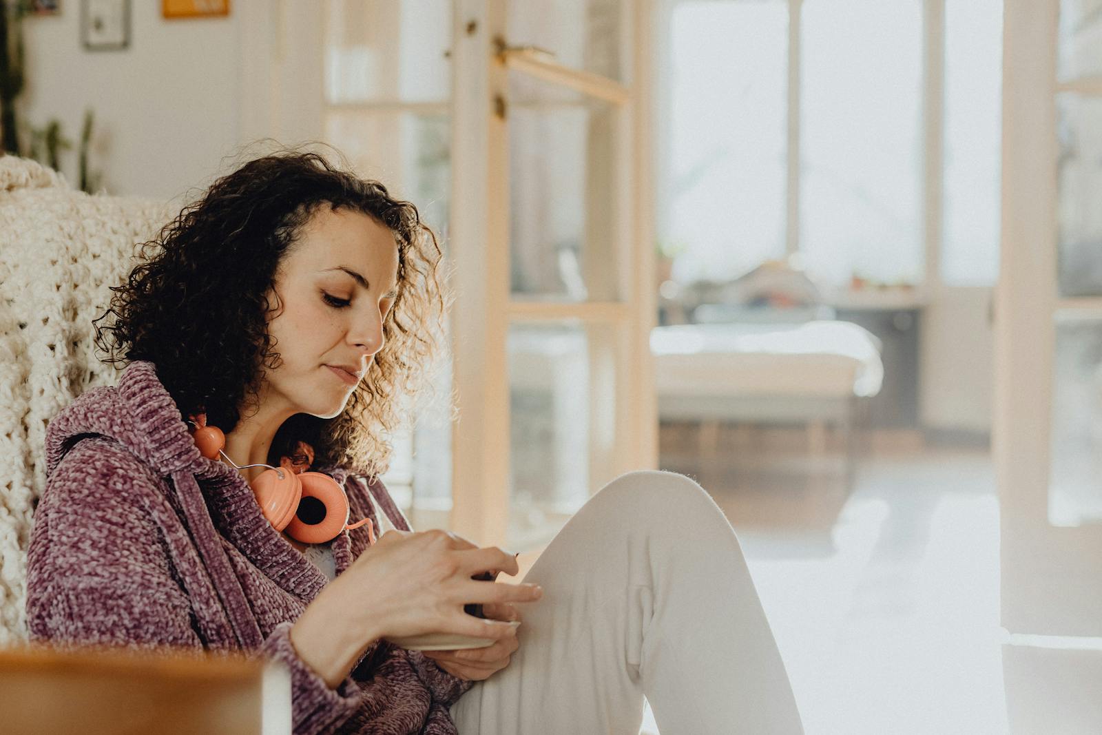 Woman relaxing at home with headphones, enjoying a quiet moment in a cozy space.