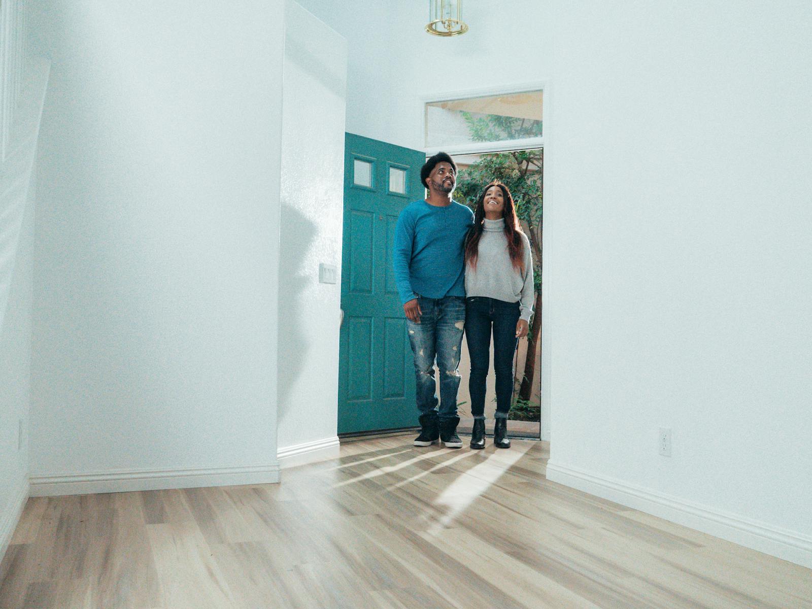 A cheerful couple stands in their new home, experiencing the excitement of ownership.