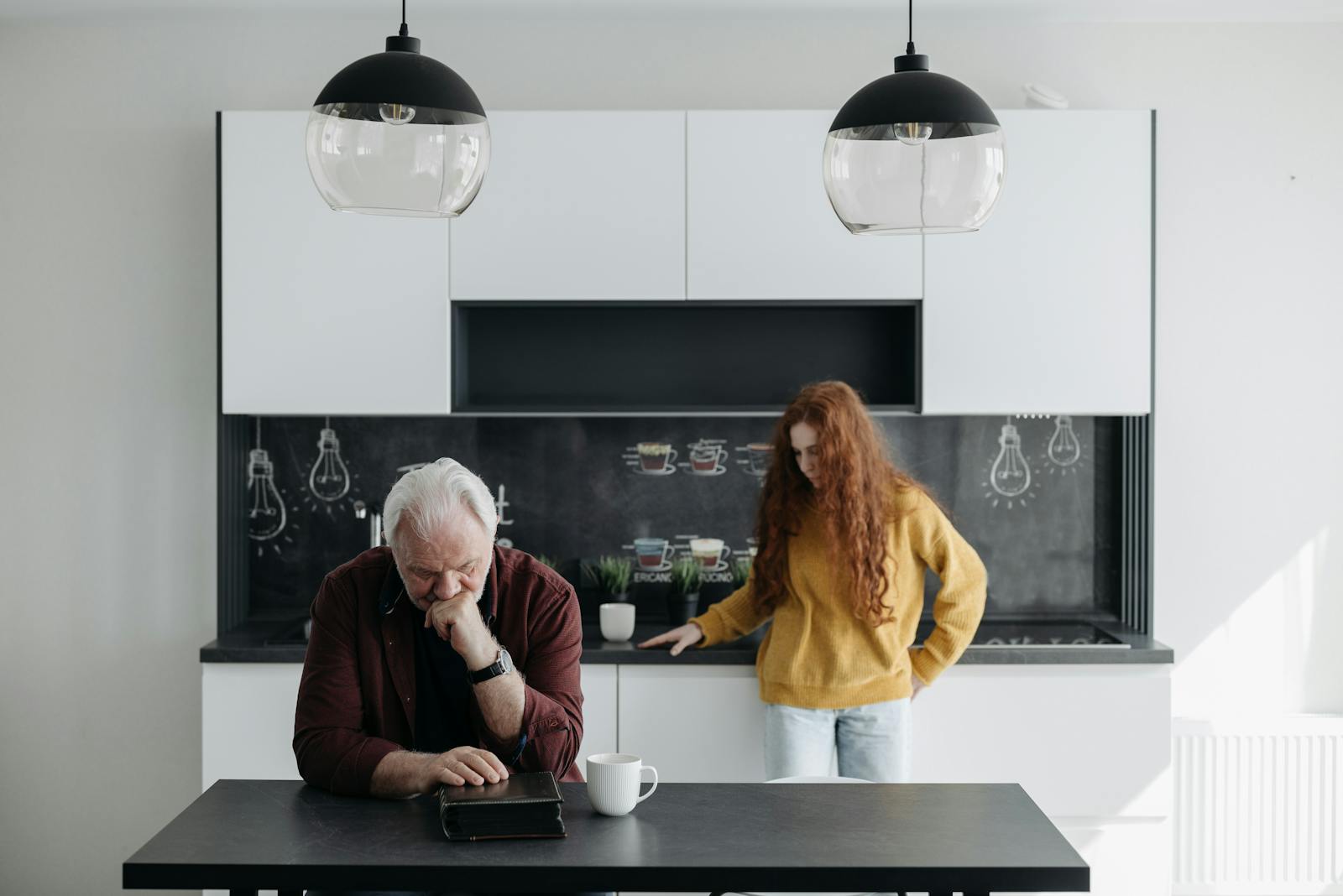 An emotional scene of a senior man and a young woman in a modern kitchen, capturing sorrow and family bond.