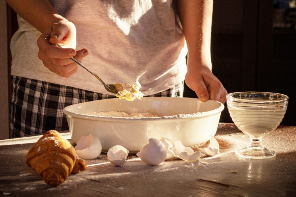 person holding stainless steel spoon and white ceramic bowl