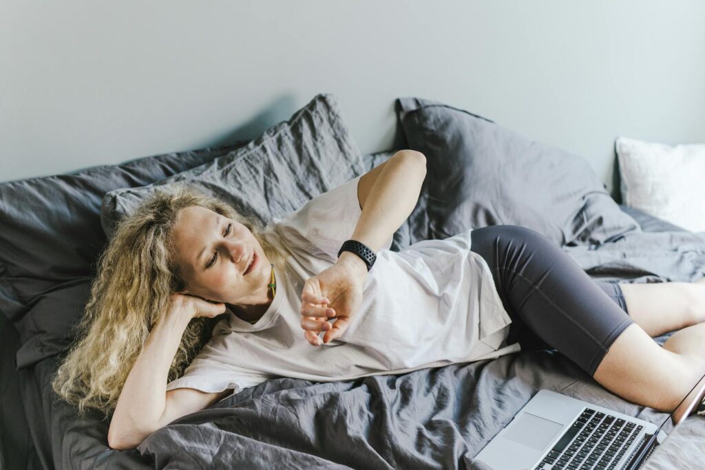 Woman reclining on bed using a laptop, enjoying a relaxing moment indoors.