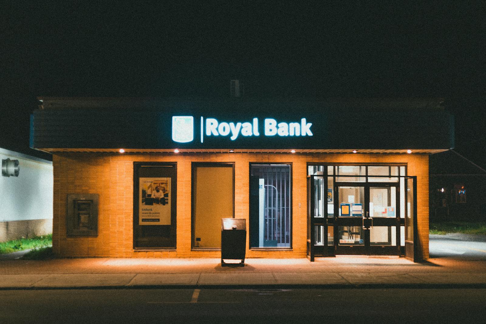 Exterior view of a Royal Bank building at night with glowing facade lights.