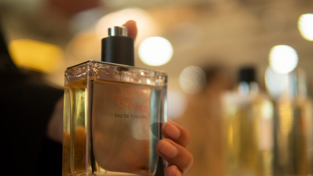 a person holding a bottle of perfume in their hand