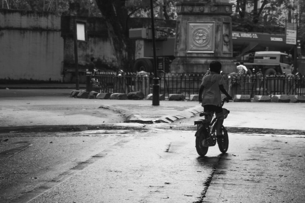 A child rides a bicycle on a wet street.