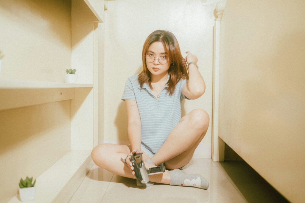 A woman sitting on the floor with a gun in her hand