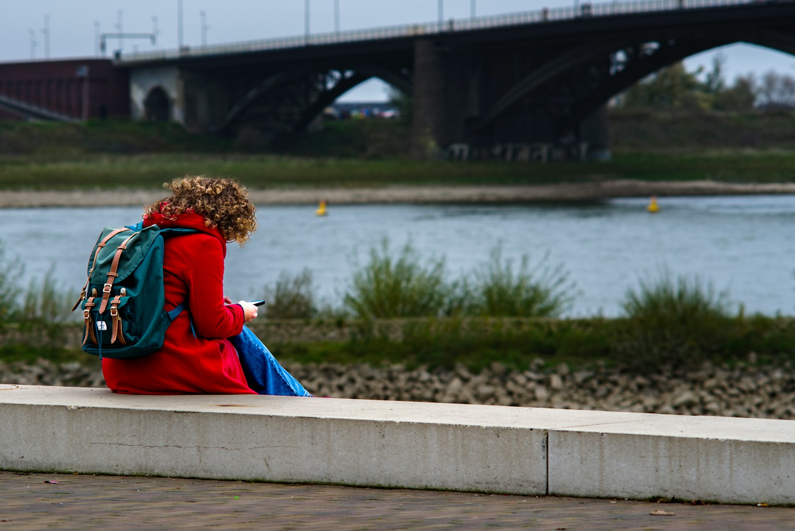 A woman sitting on a ledge looking at her cell phone